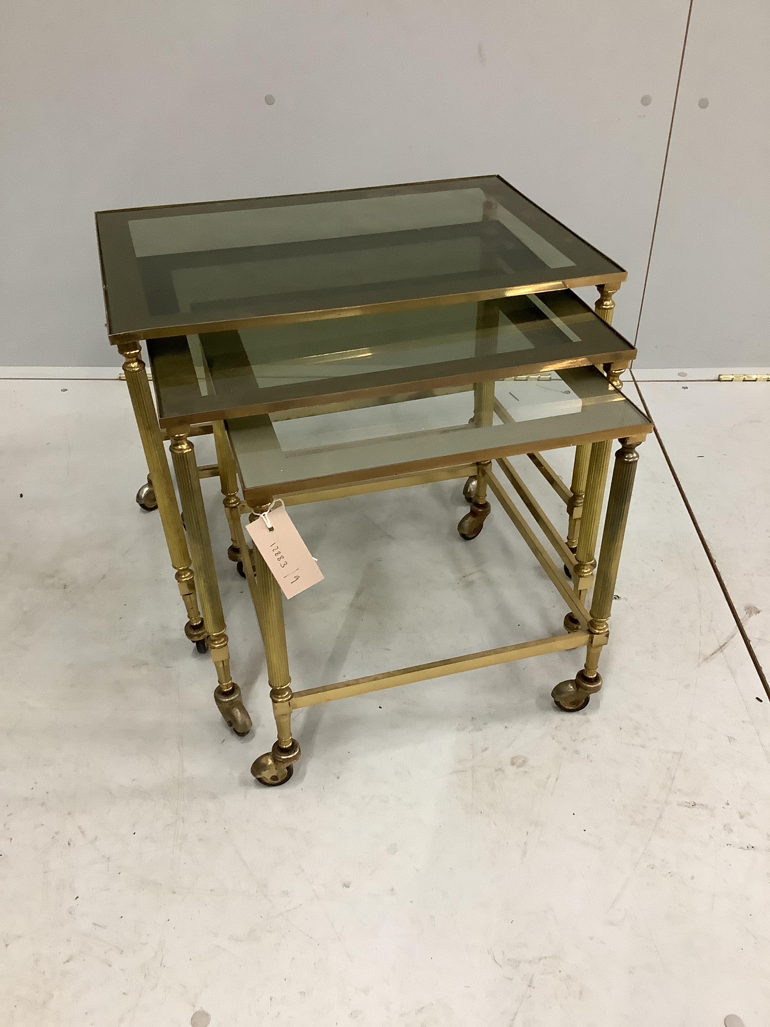 A nest of three rectangular mid century brass tea tables with smoked glass tops, width 53cm, depth 36cm, height 43cm